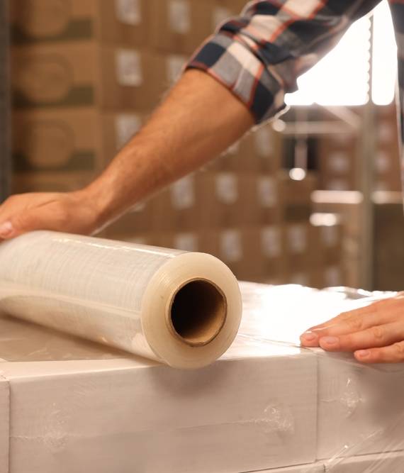 Worker,Wrapping,Boxes,In,Stretch,Film,At,Warehouse,,Closeup