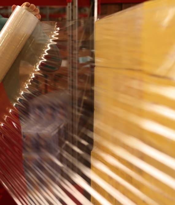 Worker,Wrapping,Boxes,In,Stretch,Film,At,Warehouse,,Closeup