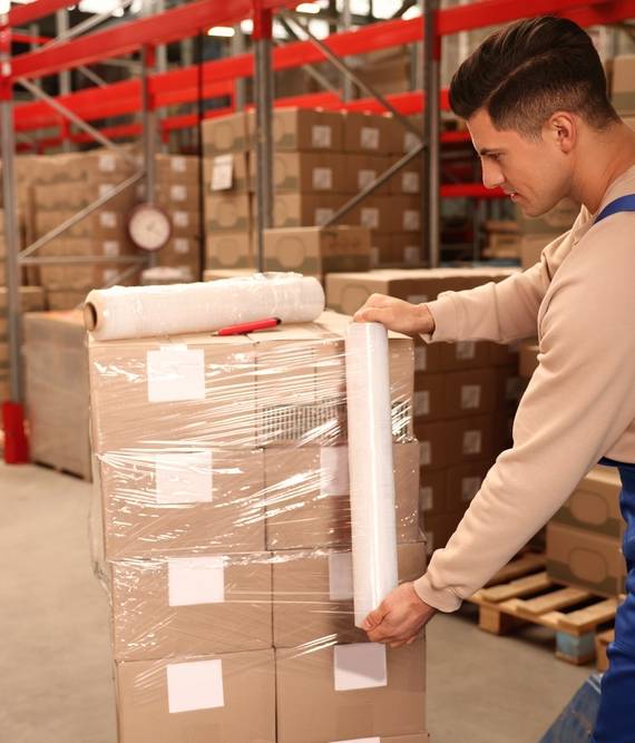 Worker,Wrapping,Boxes,In,Stretch,Film,At,Warehouse